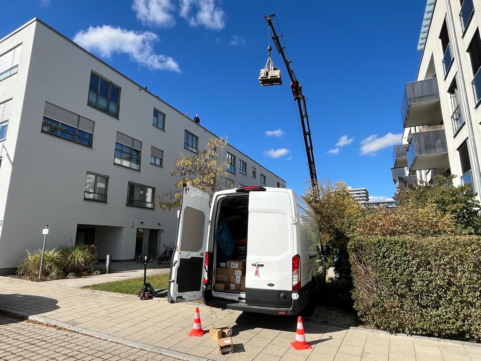 Kran hebt Solarmodule auf ein Mehrfamilienhaus in München-Schwabing